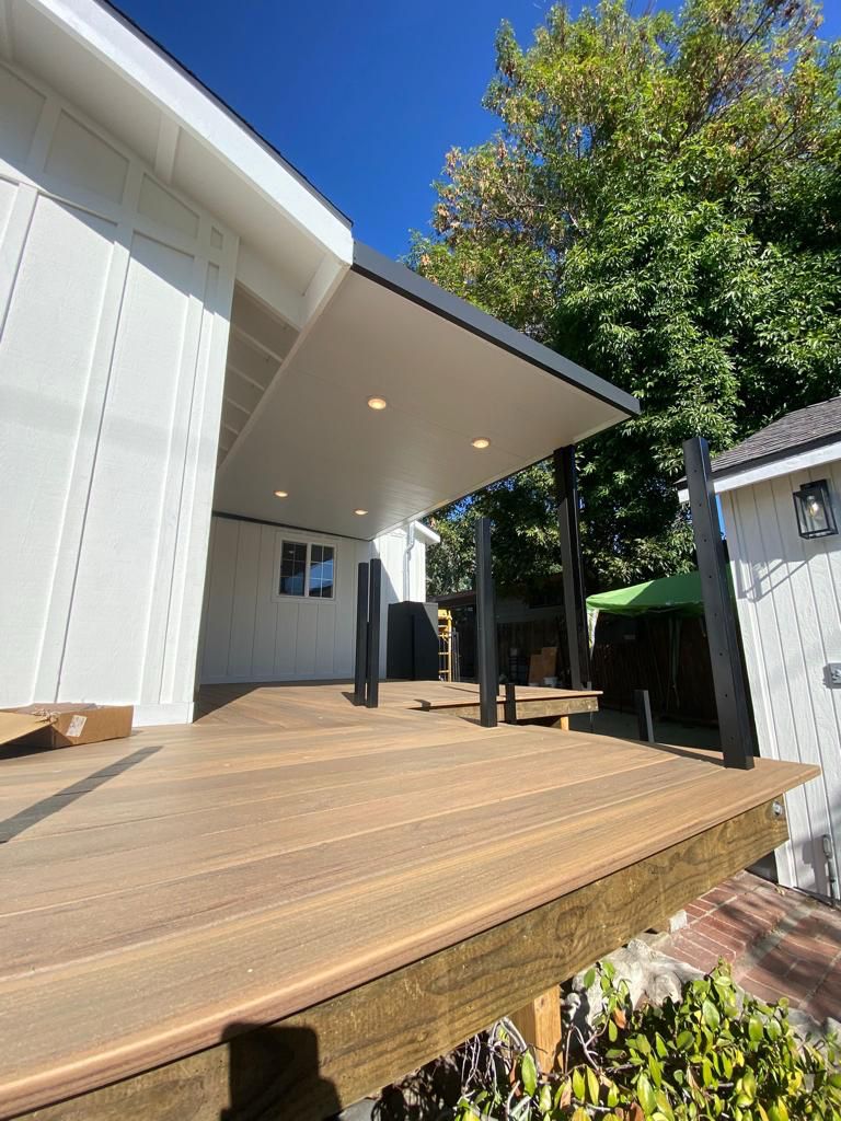 Wooden deck with overhead lighting and support posts.
